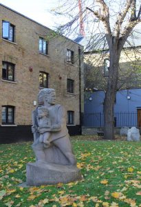 Statue of Christopher Jones holding an infant in a graveyard scattered with autumn leaves